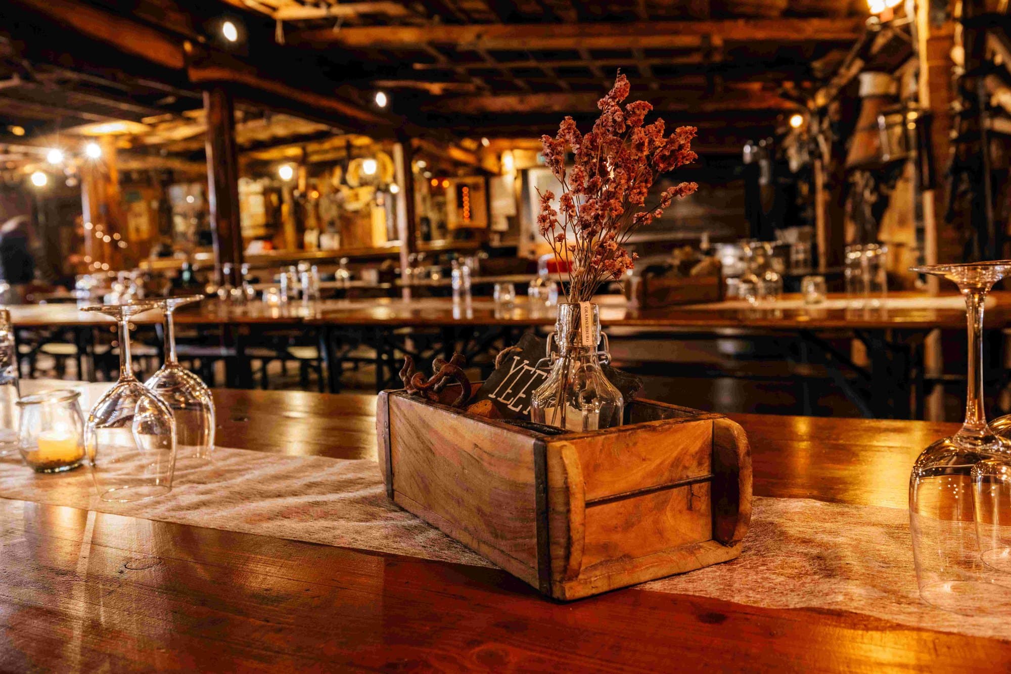 Gedeckter Tisch mit Holzkiste und Trockenblumen im Saloon