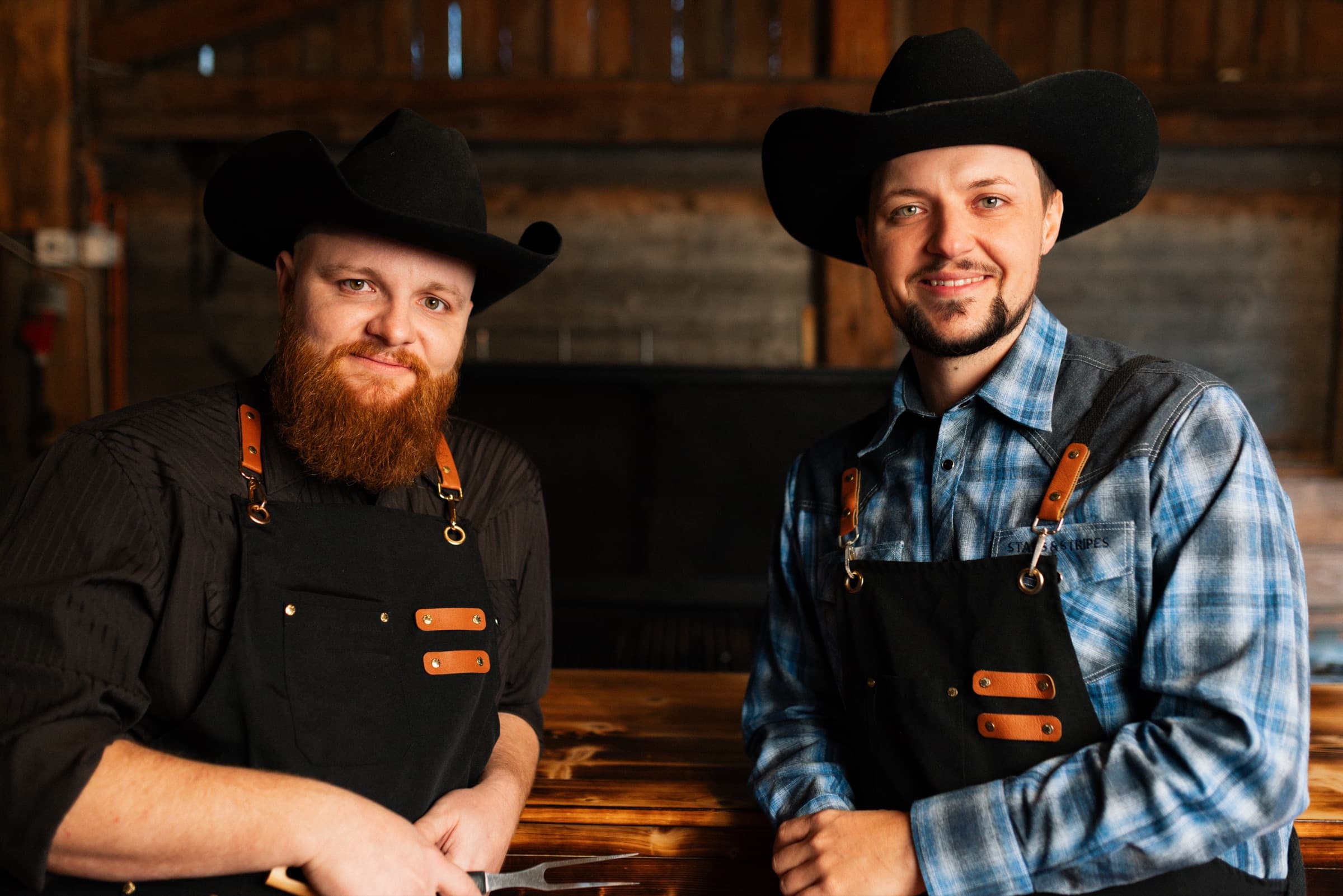 Pascal und Philipp mit Cowboyhüten und Schürzen am Smoker